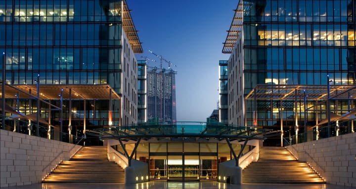 Two modern glass office buildings lit up at dusk