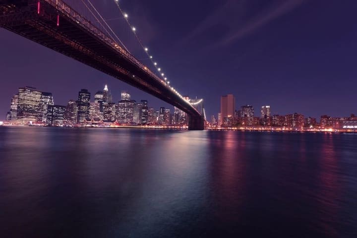 Lower Manhattan at night seen beneath the Brooklyn Bridge