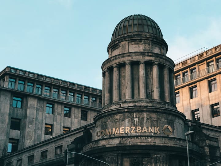 A domed Commerzbank building on a city corner under a blue sky
